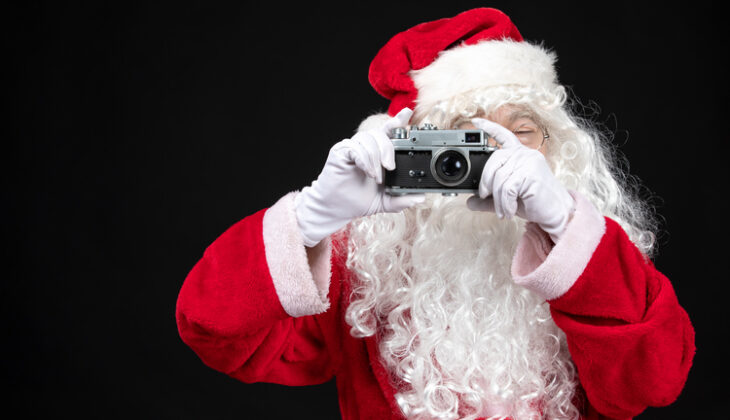 front view santa claus classic red suit holding camera Skyteach
