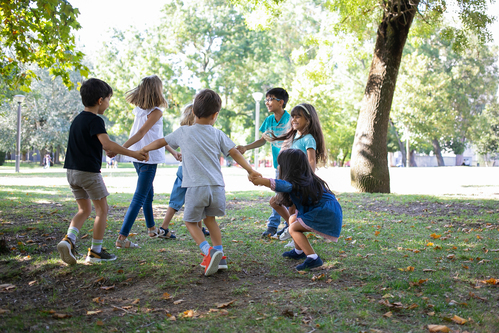 happy children playing together outdoors dancing around grass enjoying outdoor activities having fun park kids party friendship concept 1 Skyteach